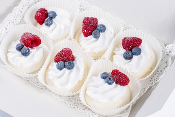 Delicious sweet cupcakes with cream and berries on light table