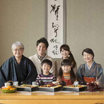 テーブルの上に並ぶおせち料理と微笑む3世代家族