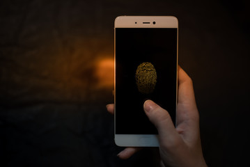Smartphone fingerprint scan technology. Try to unlock mobile phone. Dark black background.