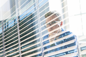 Thoughtful casual businessman wearing eyeglasses, working in office, sitting at desk, typing on...