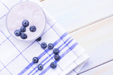 Romantic French or Rural Breakfast with a bowl of homemade youghurt with blueberries. Napkin and wood as a background, top view
