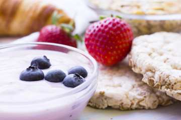 Romantic French or Rural Breakfast with youghurt, fresh berries, wheat breadcrisps and croissant, close up