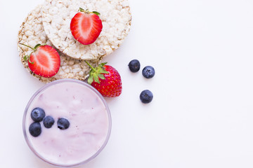 Healthy Breakfast Concept with wheat breadcrisps, fresh blueberries and strawberries and homemade youghurt on white, top view, copy space