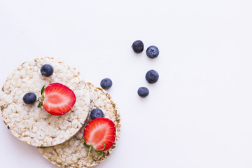 Healthy Breakfast Concept with wheat breadcrisps with fresh blueberries and strawberries on white, close up, top view, copy space