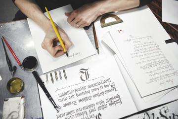 The hands of a master calligrapher. Tattoo artist the artist makes a sketch, sitting at a table in...