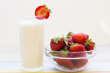 Healthy Breakfast Concept. A glass of milk and a bowl of strawberries oon white