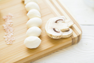Fototapeta na wymiar Preparing Food Concept. Ingredients for cooking iatalian meal with mozzarella, champignone mushrooms and sea salt on a wooden cutting board, close up, top view