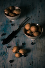 Brown edible mushrooms spilled on vintage wooden board and bowls