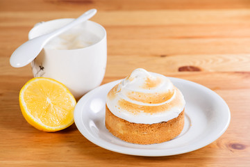 Appetizing sweet dessert. White glaze cupcake with cream and cup of cappuccino on the wooden table