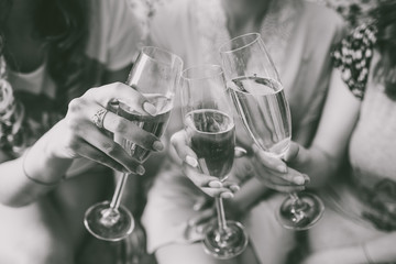 Closeup view of three female young hands holding wineglasses with champagne. Future bride with her...