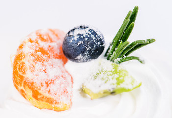 Appetizing sweet dessert. White glaze cupcake with cream, orange and blueberry on light background