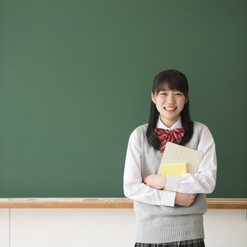 黒板の前で微笑む女子校生