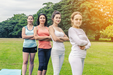 Obraz premium group of four smiling women stand up on mat in the park