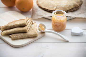 pancakes and orange jam on a light wooden background
