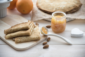 pancakes and orange jam on a light wooden background