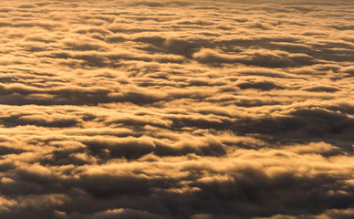 Top view on smooth golden cloud surface touching by morning sunrise. Clouds moving rapidly by wind on winter season.