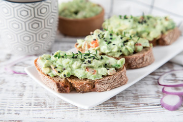 toast with guacamole, seeds and herbs. A cup of coffee. Healyhy Breakfast concept
