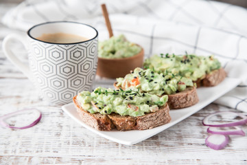 toast with guacamole, seeds and herbs. A cup of coffee. Healyhy Breakfast concept