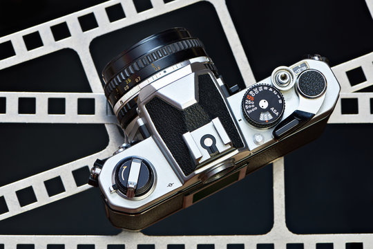 Retro SLR camera on background of perforation film