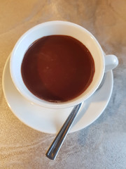 Hot chocolate, hot cocoa in white cup on table top view.