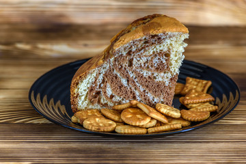 piece of cake and crackers on a black plate on a wooden background 