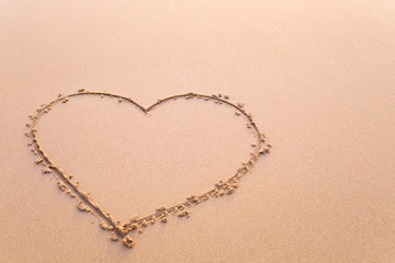 Heart drawn in the sand. Beach background.