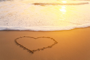 Heart in the sand on the beach at sunset.