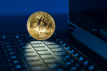 Bitcoin coin standing on keyboard of computer