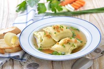 Gemüsebrühe mit deftigen schwäbischen Maultaschen, dazu getoastetes Baguette mit Butterröllchen  - Vegetable soup with Swabian-style ravioli served with butter toast