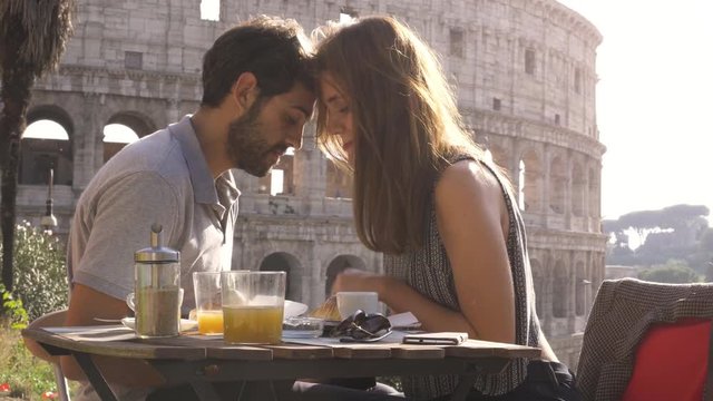 Romantic happy couple tourists in love head to head cuddling at restaurant in front of colosseum in rome at sunset emotional