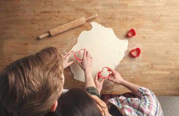 young lovely couple - boyfriend and girlfriend, making cookies in heart shape for Valentine's Day together, above view