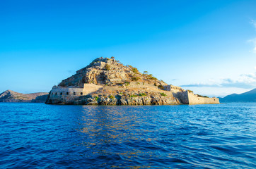 Fototapeta premium View of the island of Spinalonga with calm sea. Here were isolated lepers, humans with the Hansen's desease, gulf of Elounda, Crete, Greece. 