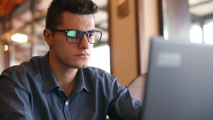 Reflections of laptop monitor screen in man's glasses. Portrait of young caucasian freelancer businessman working and browsing internet in office. Hacker at work stealing accounts database. - Powered by Adobe