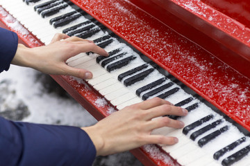 A young girl plays a red piano