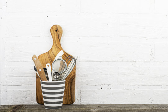 Kitchen tools, olive cutting board on a kitchen shelf against a white brick wall. selective focus