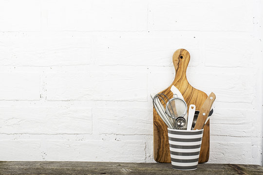 Kitchen tools, olive cutting board on a kitchen shelf against a white brick wall. selective focus