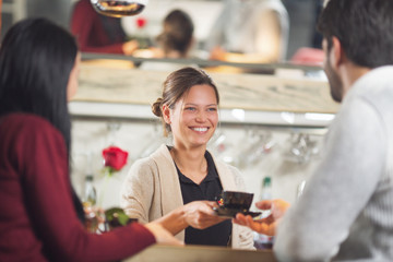 Young and beautiful barista serving coffee to customers