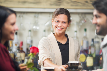 Young and beautiful barista serving coffee to customers