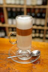 Cup of latte coffee on background of bottles.