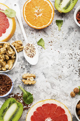 Fototapeta na wymiar Bright healthy ingredients for proper nutrition: fruits, nuts, berries, superfood, orange, grapefruit, almonds, dried apricots, figs, dates, raisins, walnuts, chia seeds, quinoa. Top View.