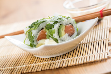 Modern Lachs Avocado Inside Out California Sushi Rolle mit Rucola Topping 