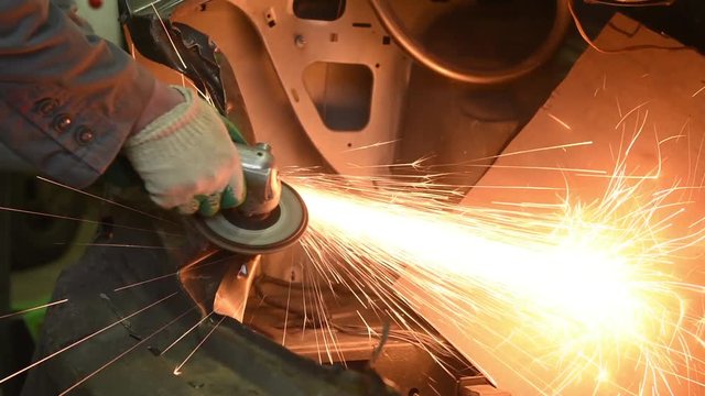 collision repairs service. mechanic grinding car body by grinder