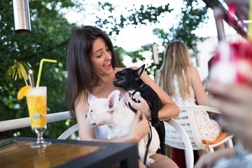 Beautiful young woman with sunglasses sitting in cafe with her adorable French bulldog puppy. People with dogs theme.