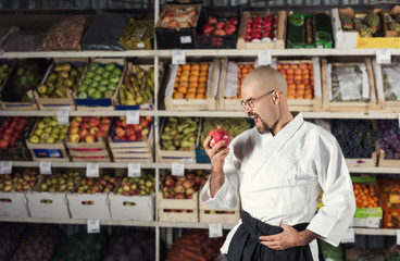 A man against the background with racks with fruits and vegetables dressed in Japanese kimono and hakama. Fruitarianism concept