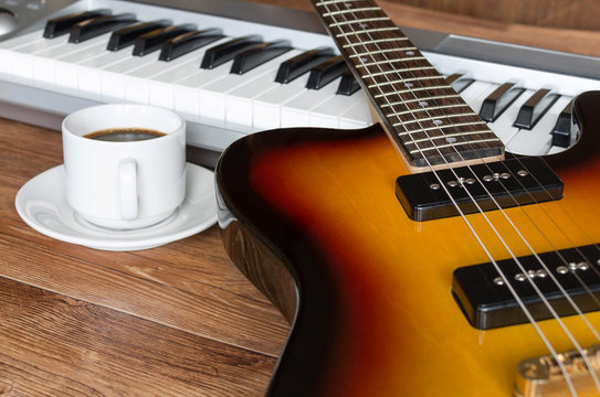 Electro guitar, piano and cap of coffee