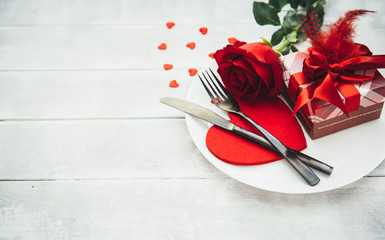 Valentines day table setting with plate, fork, knife, ribbon and rose. background