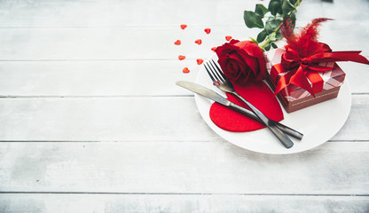 A single red rose with red heart message card on the white dish.Image of dinner on Valentines day