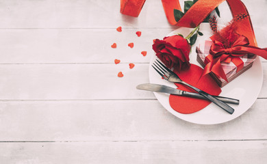 Valentine's day table setting. Table set with plate, knife and fork on white wooden background. Top view and copy space. Love concept.