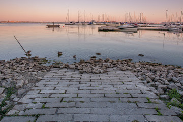 Sunset view of brick path leading into harbour with marina in background in Burlington, Ontario