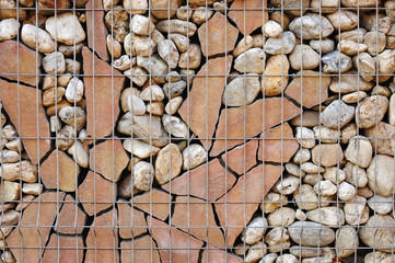 The fence is laid out of stone and fastened with metal brackets